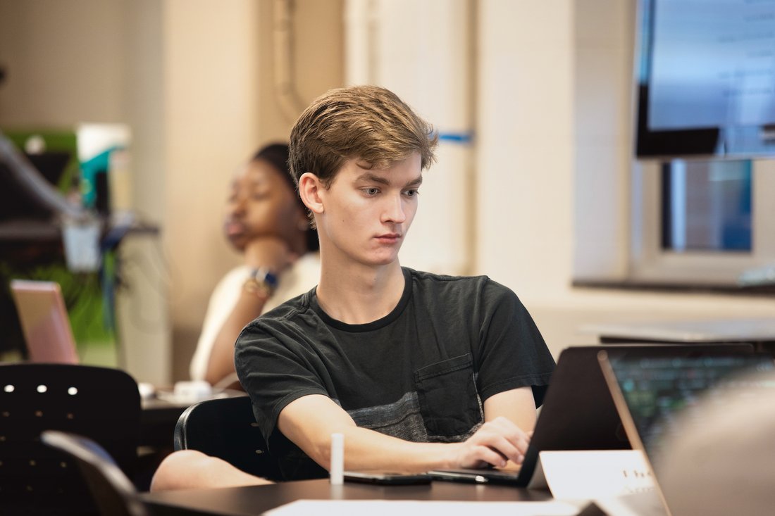 Information management student sits in classroom at his computer.