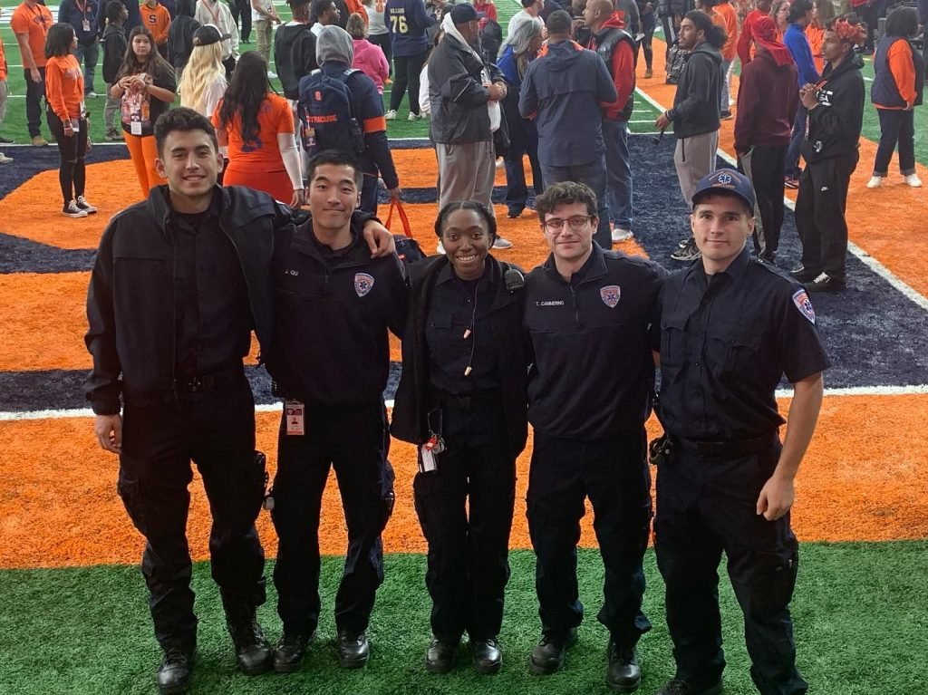 A group of ambulance personnel standing together, smiling at camera