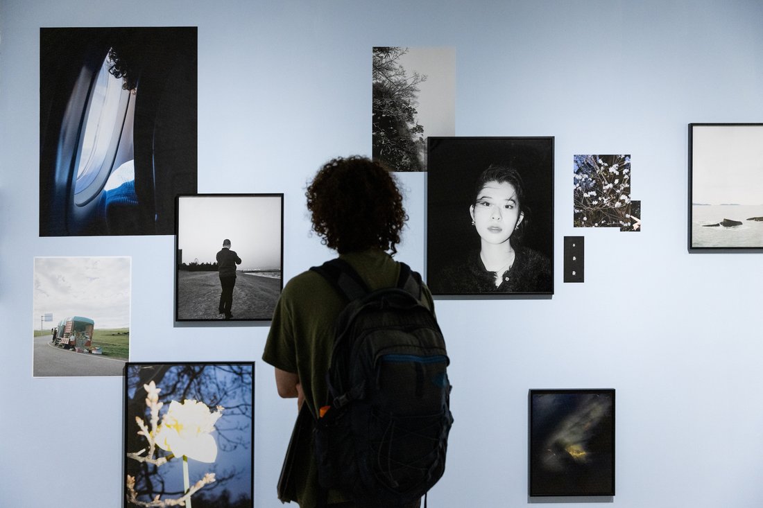A person looks at a wall of photographs in a gallery.