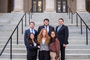 Group of students standing on stone steps outside a building.