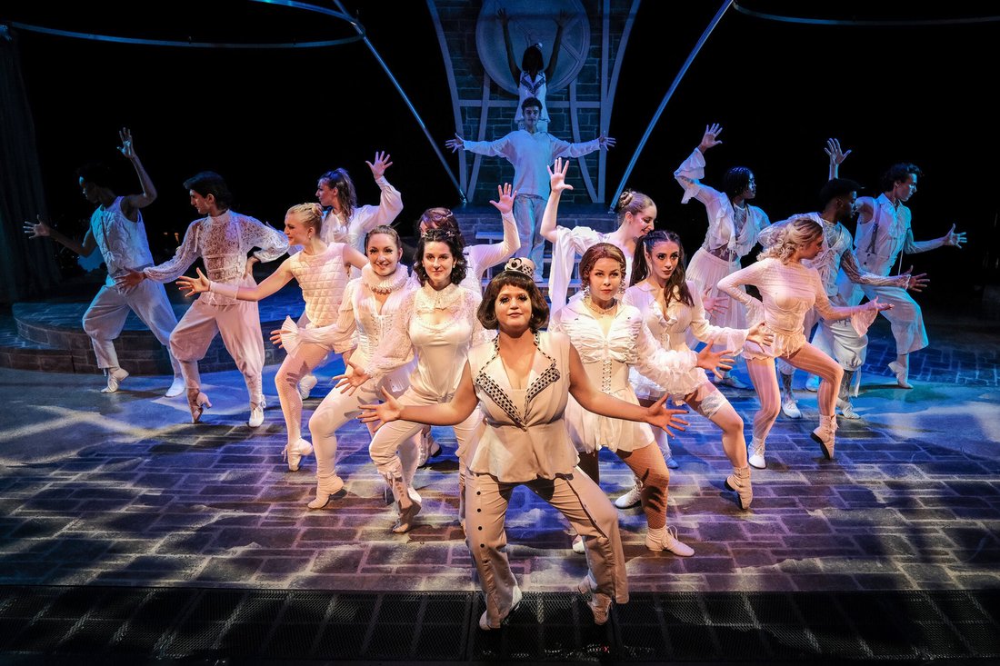 The cast of "Pippin" performs a dance number in white costumes on stage.