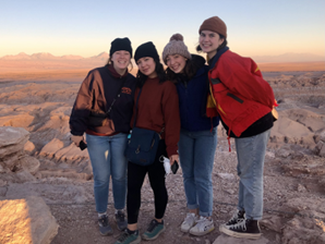 Students standing on rocks at sunset