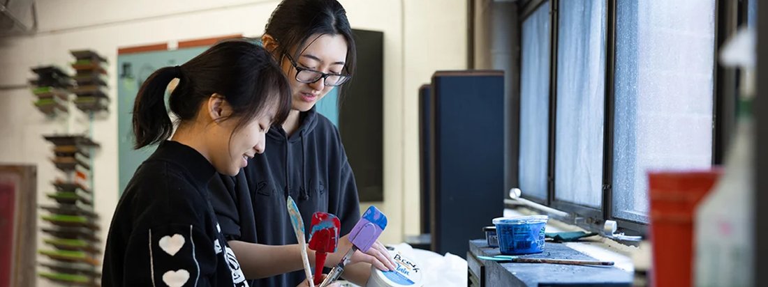 Two art students work on a class project together.