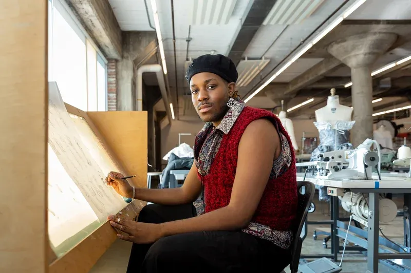 Student sitting at desk drawing.