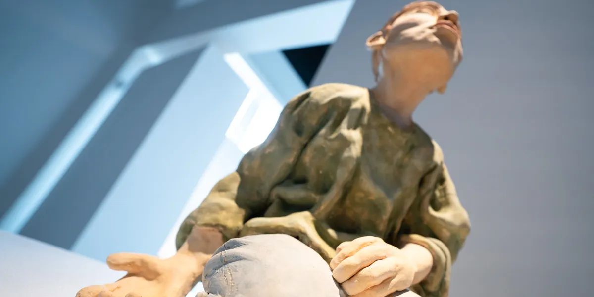 Sculpture of a kneeling person who is looking up to the ceiling.