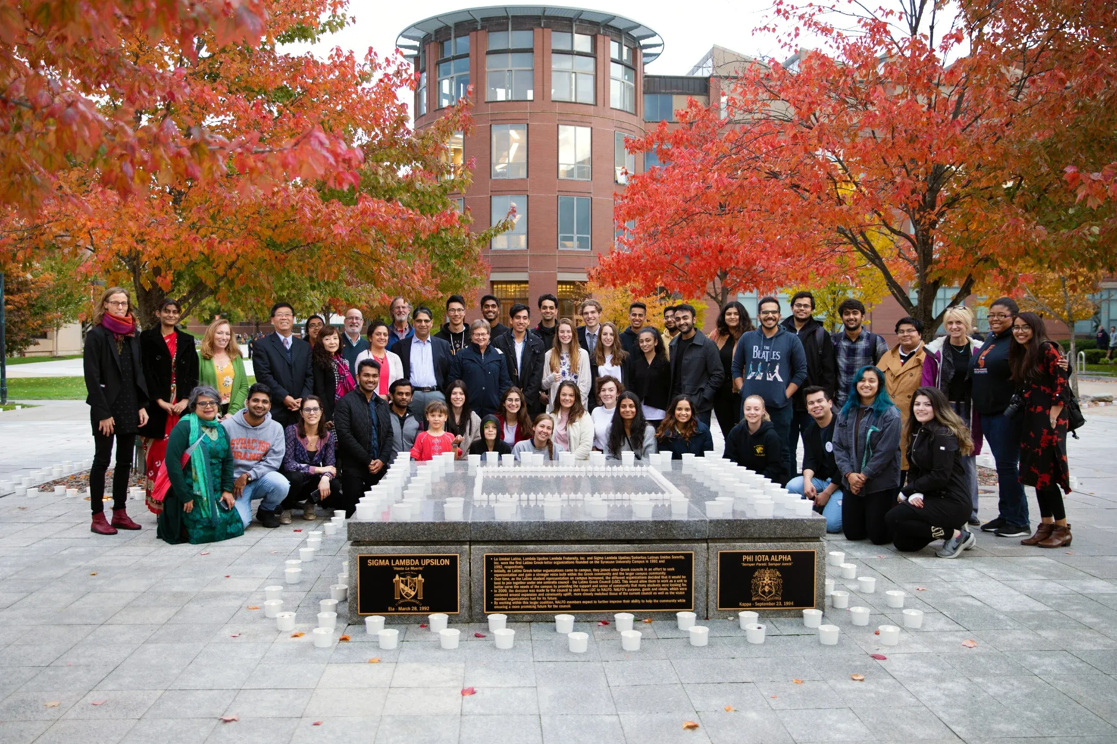 Group shot of people on campus celebrating Diwali, with candles in front of them and fall foliage behind.