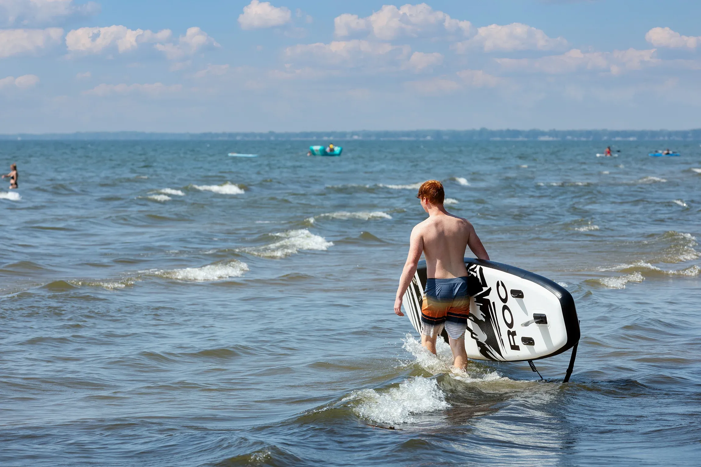 Man with surfboard stands in lake.